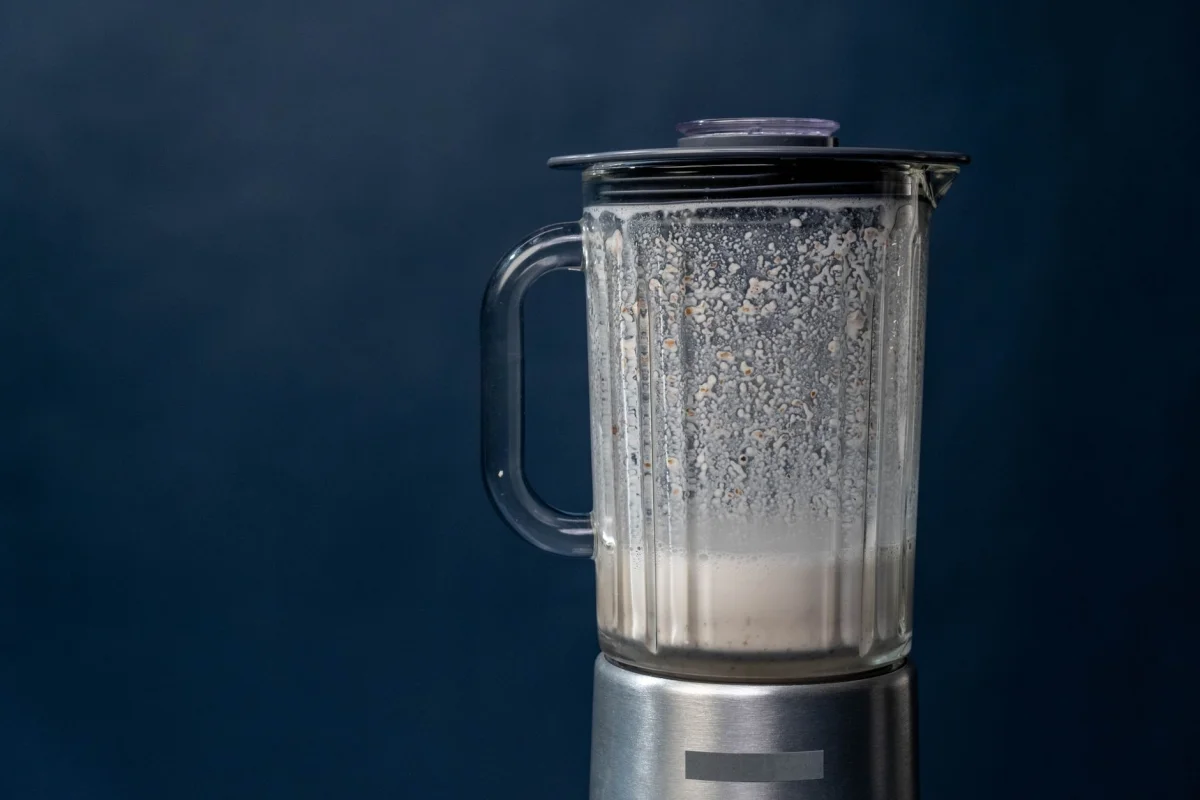 Batido proteico cremoso en vaso alto con pajita sobre encimera de cocina