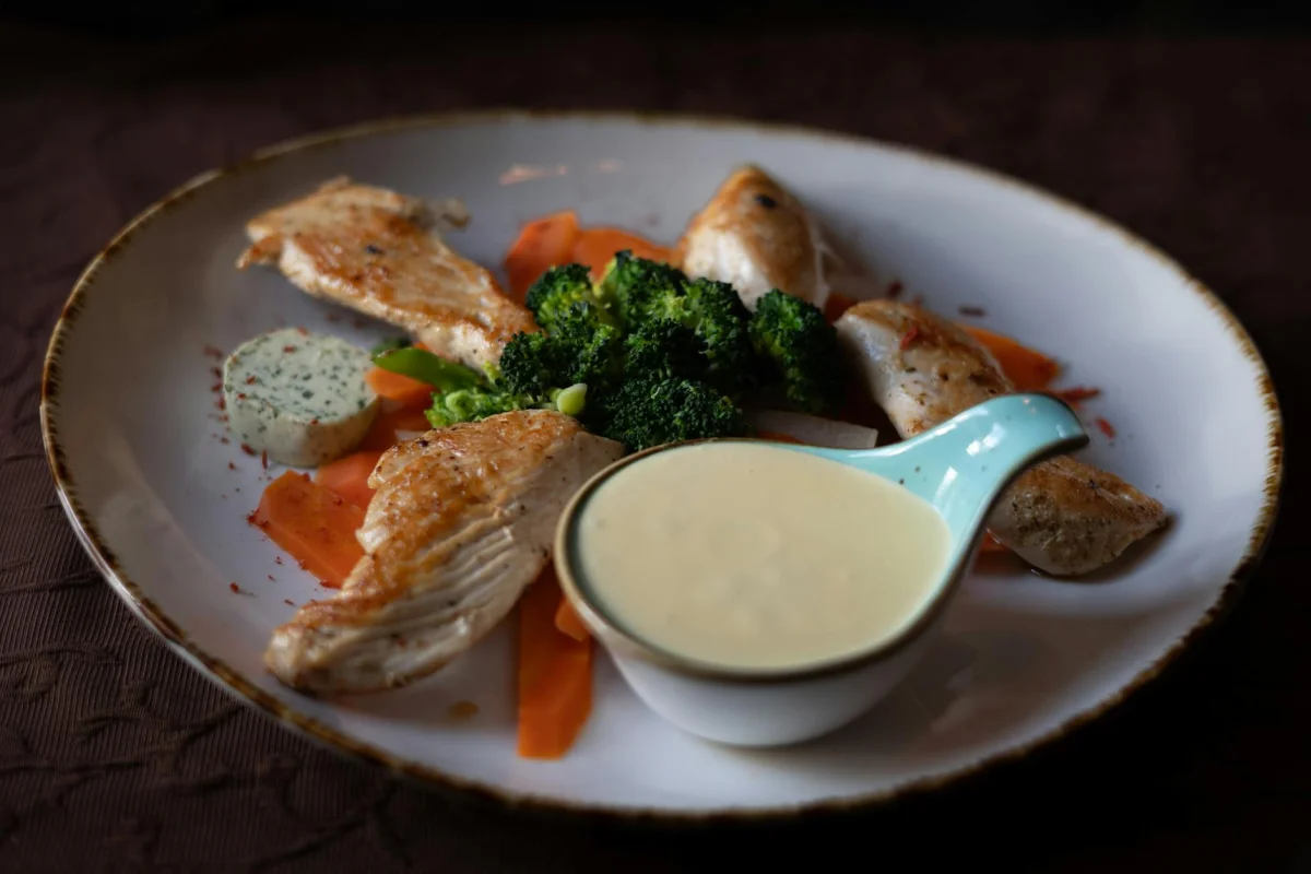 Pechuga de pollo a la plancha junto a brócoli al vapor con gajos de limón en un plato blanco