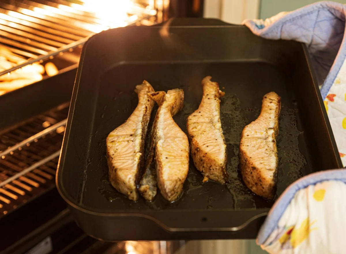 Filete de salmón cocinado en bandeja con espárragos verdes y rodajas de limón