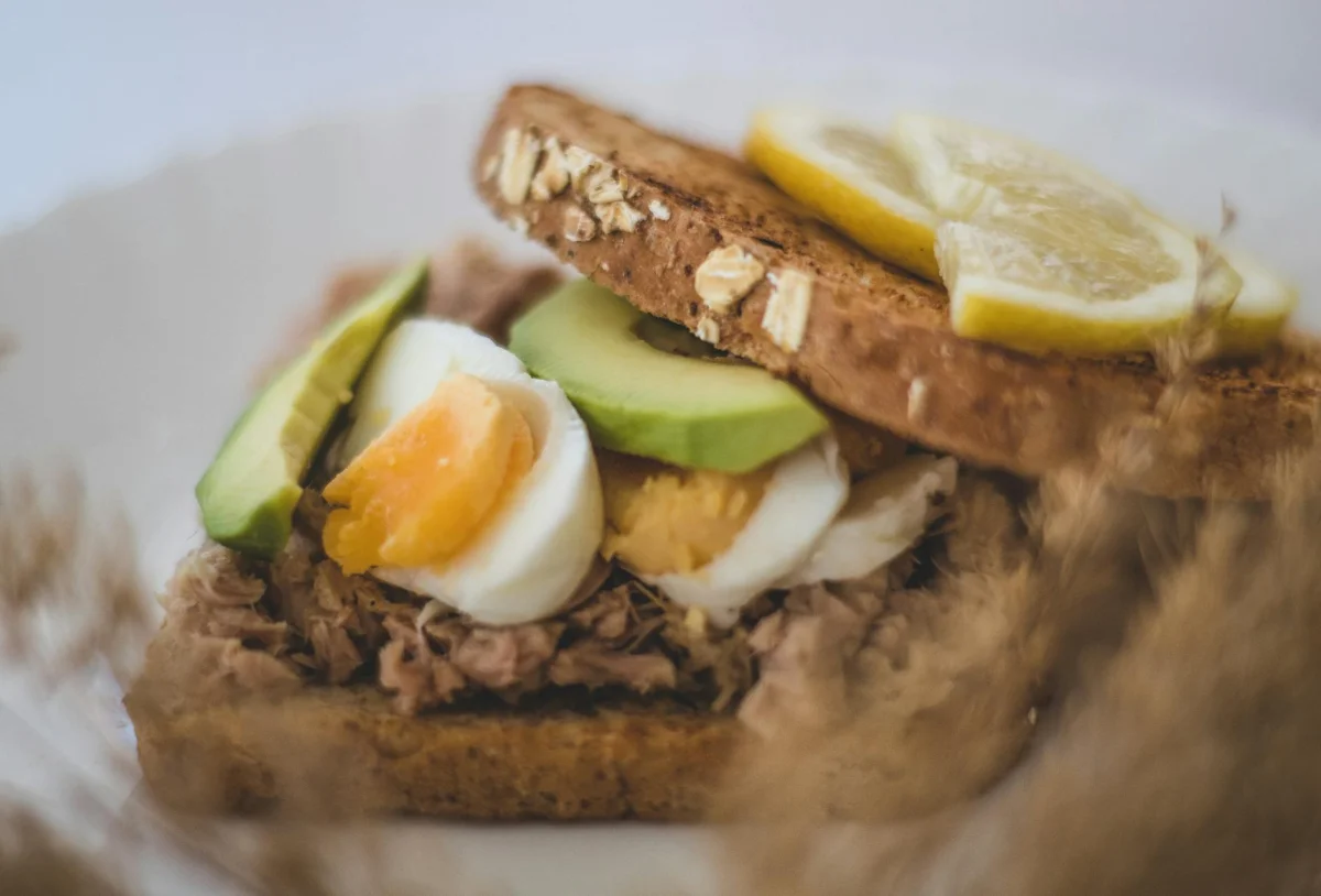 Tostada de pan integral con atún desmenuzado, aguacate en rodajas y semillas de sésamo